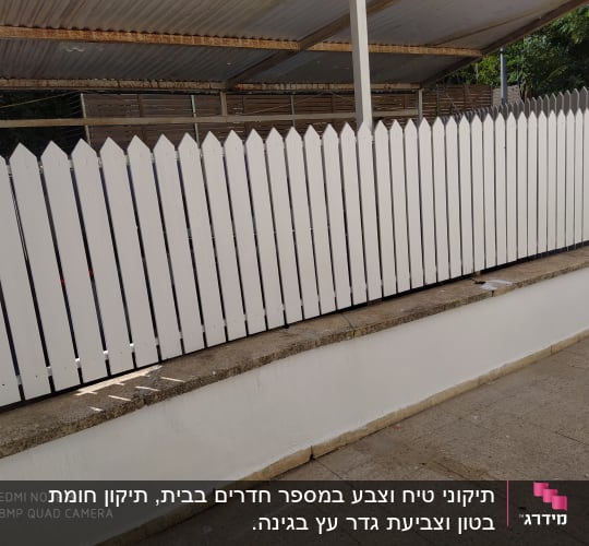 גדר עץ צבועה בלבן עם גג מתכת מעל